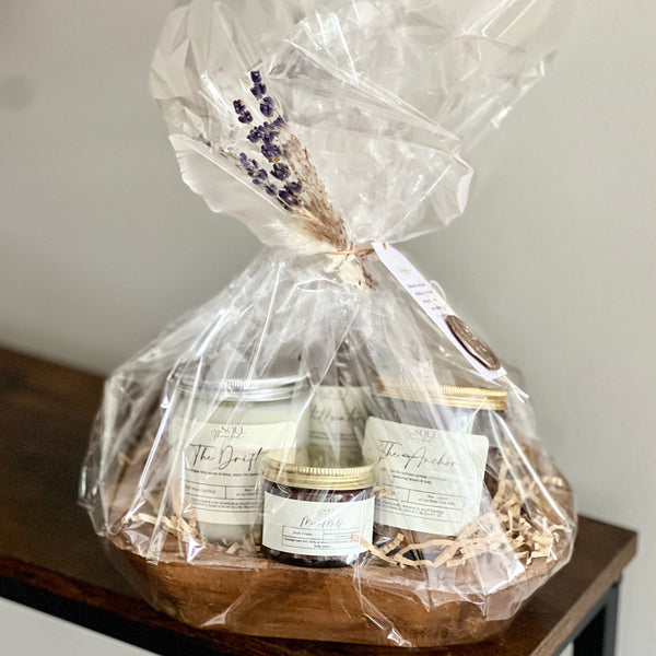 Gift basket with products wrapped in clear cellophane on a wooden table.